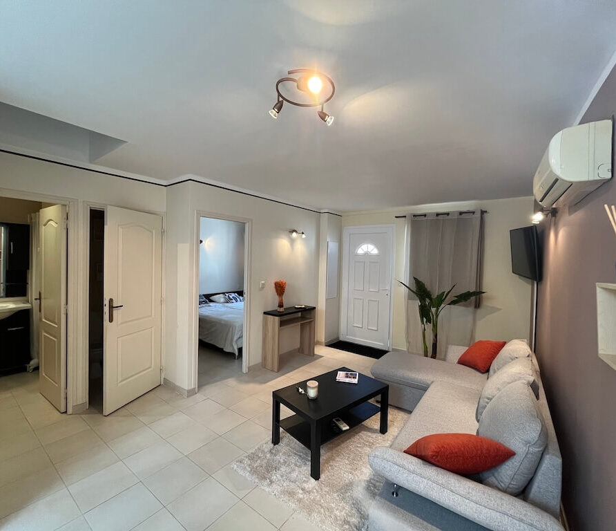 Salon avec canapé d’angle et accès chambre dans mini villa à Favone proche Solenzara en Corse